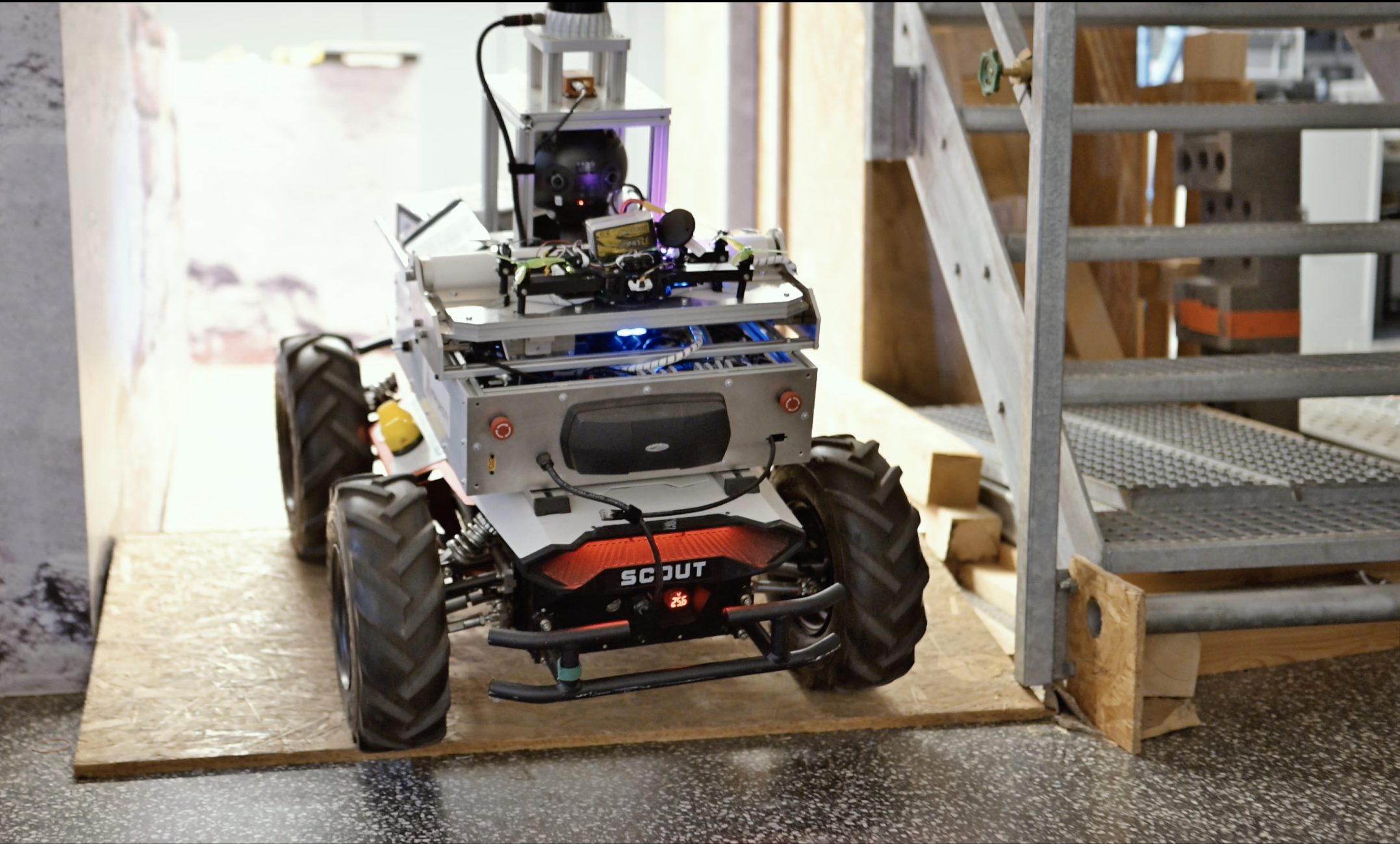 Rescue Robot Scout ascends a wooden ramp inside a building.